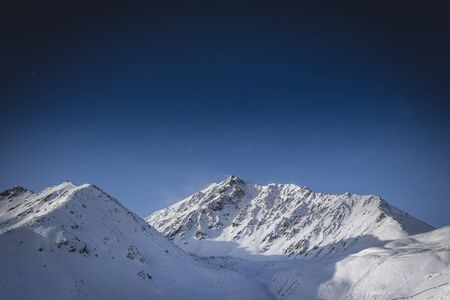 Mountain peak in the snow. Clear blue sky.