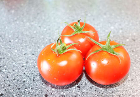 Red juicy tomatoes on a gray table, background View of a harvest of tomatoesの写真素材