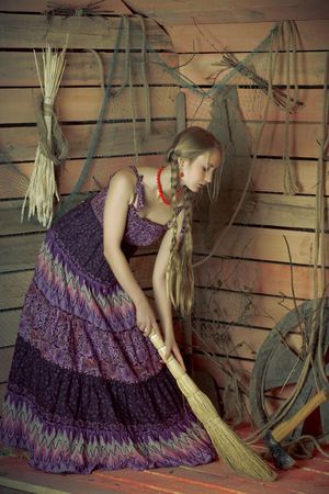 Woman with a broom sweeps the floor in a wooden house.の写真素材