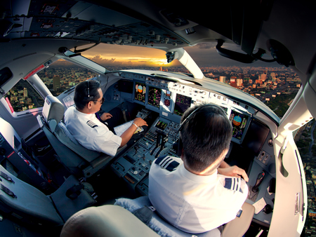 Cockpit of modern passenger jet aircraft. Pilots at work. Aerial view of modern city business...