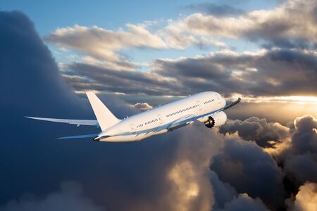 The passenger plane flies away beyond the horizon. The plane flies over the clouds during the sunset. Rear view of aircraft.の写真素材