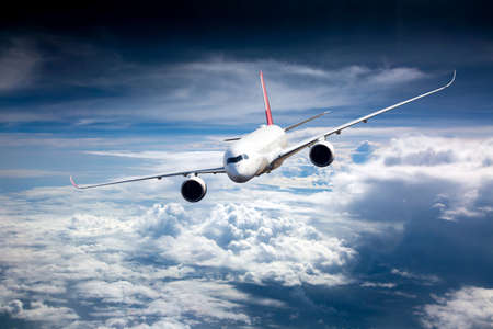 Passenger plane in flight. Aircraft flies high in the blue sky above the clouds. front view. Left heeling.の写真素材