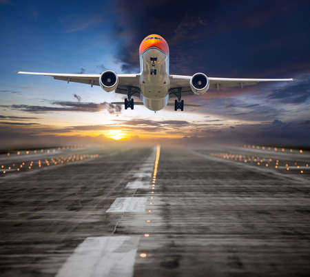 Orange passenger plane in flight. Aircraft takes off from the airport runway during the sunset....