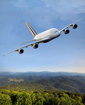 Passenger double decker plane in flight. Airplane fly high above the green hills. Front view of...