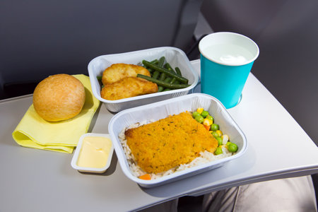 food in airplane. butter and bread. Hot dish in the aluminum lunch box: fish, chicken, rice and vegetables. Drink: water.の写真素材