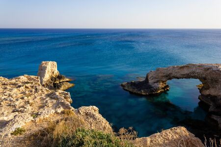 Beautiful view of the blue Mediterranean sea and the rock arch on a Sunny day from Cape Greco in Cyprus. Stone landscape of Ayia NAPA. Yellow rocks in the sea.の写真素材