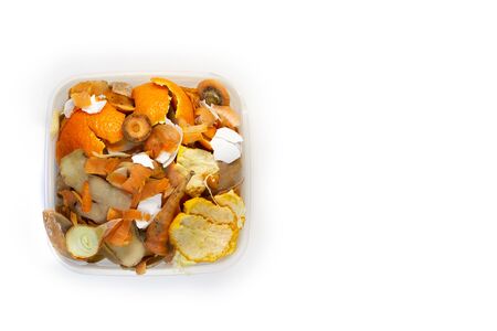 Food waste carrots, bananas, potatoes, oranges, onions, eggshells in a container on a white background. Top view. Flat lay. Waste for recycling. Responsible disposal of household food wastage in an environnmentally friendly way by recycling.の写真素材