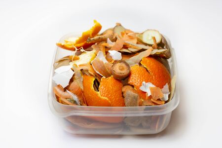 Food waste carrots, bananas, potatoes, oranges, onions, eggshells in a container on a white background. Close up. Waste for recycling. Responsible disposal of household food wastage in an environnmentally friendly way by recycling.の写真素材