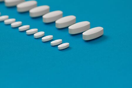 White tablets on a blue background close-up. Macro pills. Medical care for flu and colds. Protection...