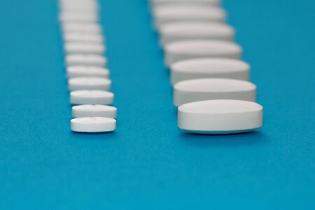 White tablets on a blue background close-up. Macro pills. Medical care for flu and colds. Protection...