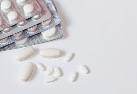 White pills in a blister pack on white background close-up. Painkillers. Protection from coronovarus...