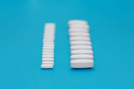 White tablets on a blue background close-up. Macro pills. Medical care for flu and colds. Protection from Covid19の写真素材