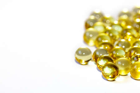 Yellow fish oil in capsules on a white background. Omega3 vitamins close-up. Capsules fish oil macro. Vitamins for health.の写真素材
