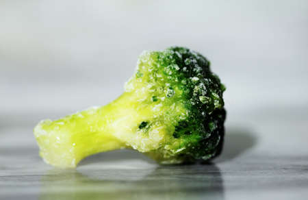 Frozen green fresh broccoli on a marble table close-up. Macro. Storage of frozen food. Frozen...