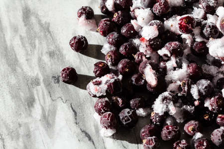 Frozen berries of black currant on a gray background. Storage of frozen food. Frozen product. Black...