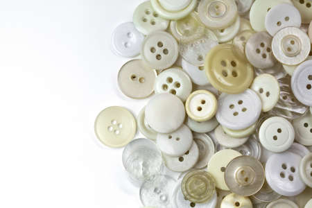 White and beige buttons on a white background. Old vintage buttons close up. Copy space. Top view. The background is made of buttons in natural shades. Flat lay. Decor for handmade and craft.の写真素材