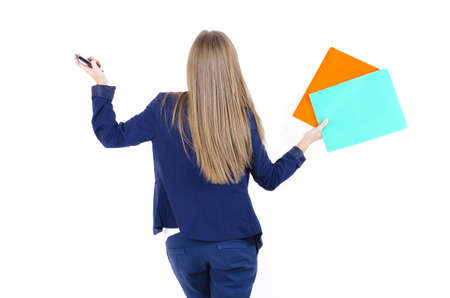 Girl in business clothes in a jacket and trousers turned back holding hands raised up and holding mobile phone in one and in another foldersの写真素材