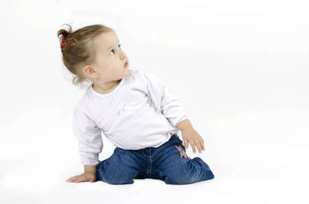 cute little girl squatting on his knees and leaning with one hand on the ground looking up curiouslyの写真素材