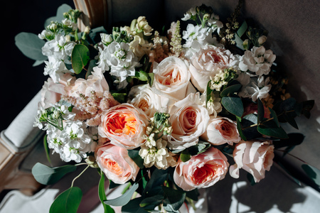 Wedding bouquet with white flowers, roses, greens and ribbons on the chairの写真素材