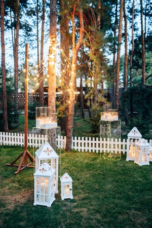 Decorated area with white wooden candle lamps and flowers on the grassの写真素材