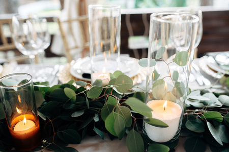 Decorated table with gold plates, candles and greens on the white tableclothの写真素材