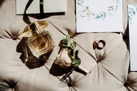 Wedding rings with perfume, guestcard and rose on the beige backgroundの写真素材