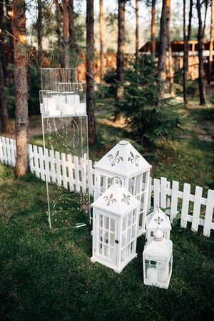 Decorated area with white wooden candle lamps and flowers on the grassの写真素材