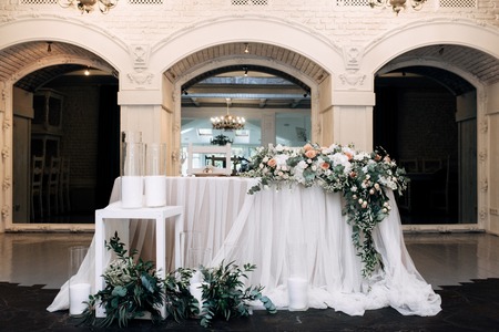 Wedding table decorated with candles, flowers and eucalyptus in an ancient building with archesの写真素材