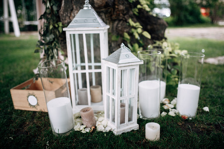 Outdoor area with white wooden old-fashioned lanterns and candles on the grassの写真素材