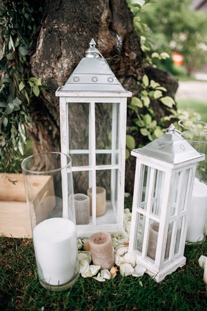 Outdoor area with white wooden old-fashioned lanterns and candles on the grassの写真素材