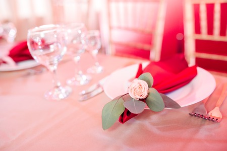 details on table decor - small rose in corner of burgundy napkin on a plateの写真素材
