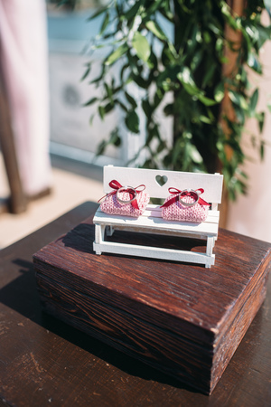 Small pink pillows with wedding rings on decorative white benchの写真素材