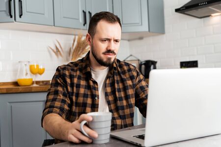 The guy works on a laptop with a serious faceの写真素材