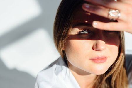 close up portrait of a beautiful girl. She covered her face with her hand, only one blue eye and the lower part of the face are visibleの写真素材