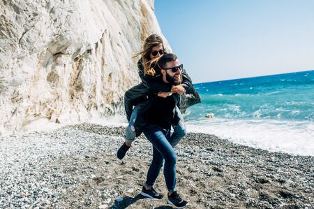 happy couple in the leather jackets running on the beachの写真素材