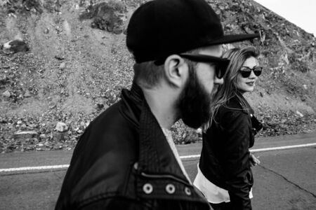 Black and white photo of stylish couple in love. A guy with a beard and a cap, a girl in a leather jacketの写真素材