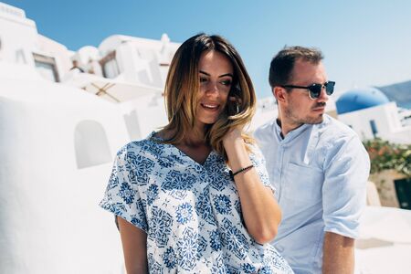 Happy beautiful couple in the Mediterranean landscape. Girl in a light dress, a guy in a summer blue...