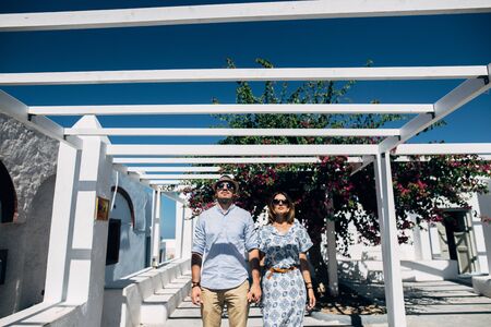 A young couple is standing under a white pergola with braided flowersの写真素材