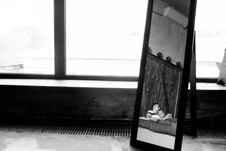 Couple cuddling in bed. Reflection in the mirror. Black and white photoの写真素材