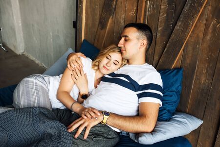 Portrait of a couple in bed in casual wear. They gently hug with their eyes closed.の写真素材
