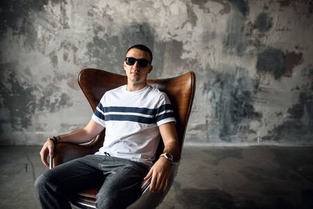 The guy in the studio sits in armchair in sunglassesの写真素材