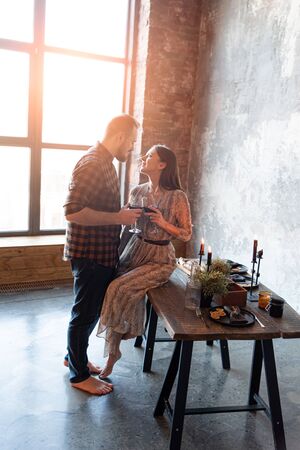 Romantic dinner. Couple in casual clothes with glasses of red wine near a loft style tableの写真素材
