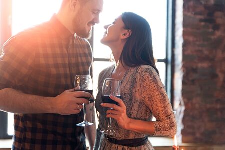 Valentine's Day. Portrait of a young guy with a girl with glasses of wine in the sunset lightの写真素材