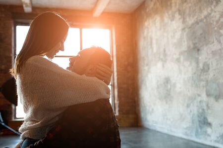 A couple in love hugs each other in sunset light from a large window. Love story indoorsの写真素材