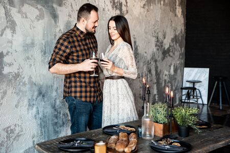 Festive table with candles. Romantic couple with glasses of wine celebrate Valentine's Day.の写真素材