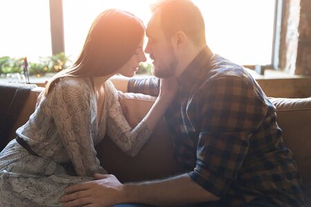 Portrait of a loving couple in warm sunlight indoors. They gently touch each other.の写真素材