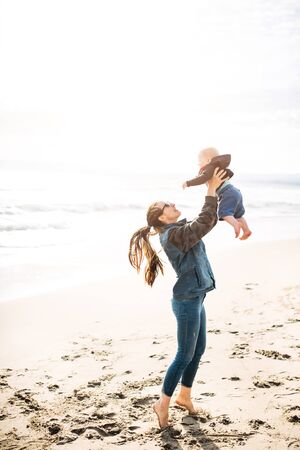 a happy family. mom holds her baby boy in her arms on the beachの写真素材
