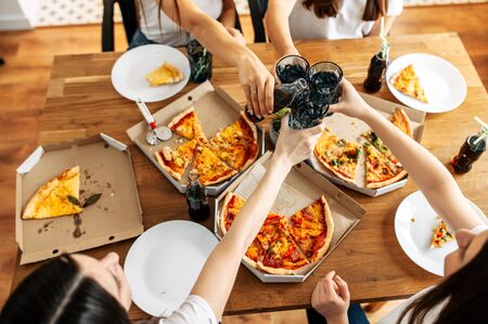 Pizza party. Cheers with glasses in hands above delicious pizza. Top viewの写真素材