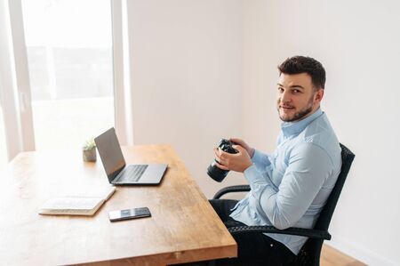 Content manager at work. A young handsome man in the office looks through a photo shoot on the...