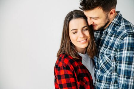 Love you so much. The guy gently kisses the girl on the temple, she smiles happily. They are in casual checkered shirts. Close portraitの写真素材